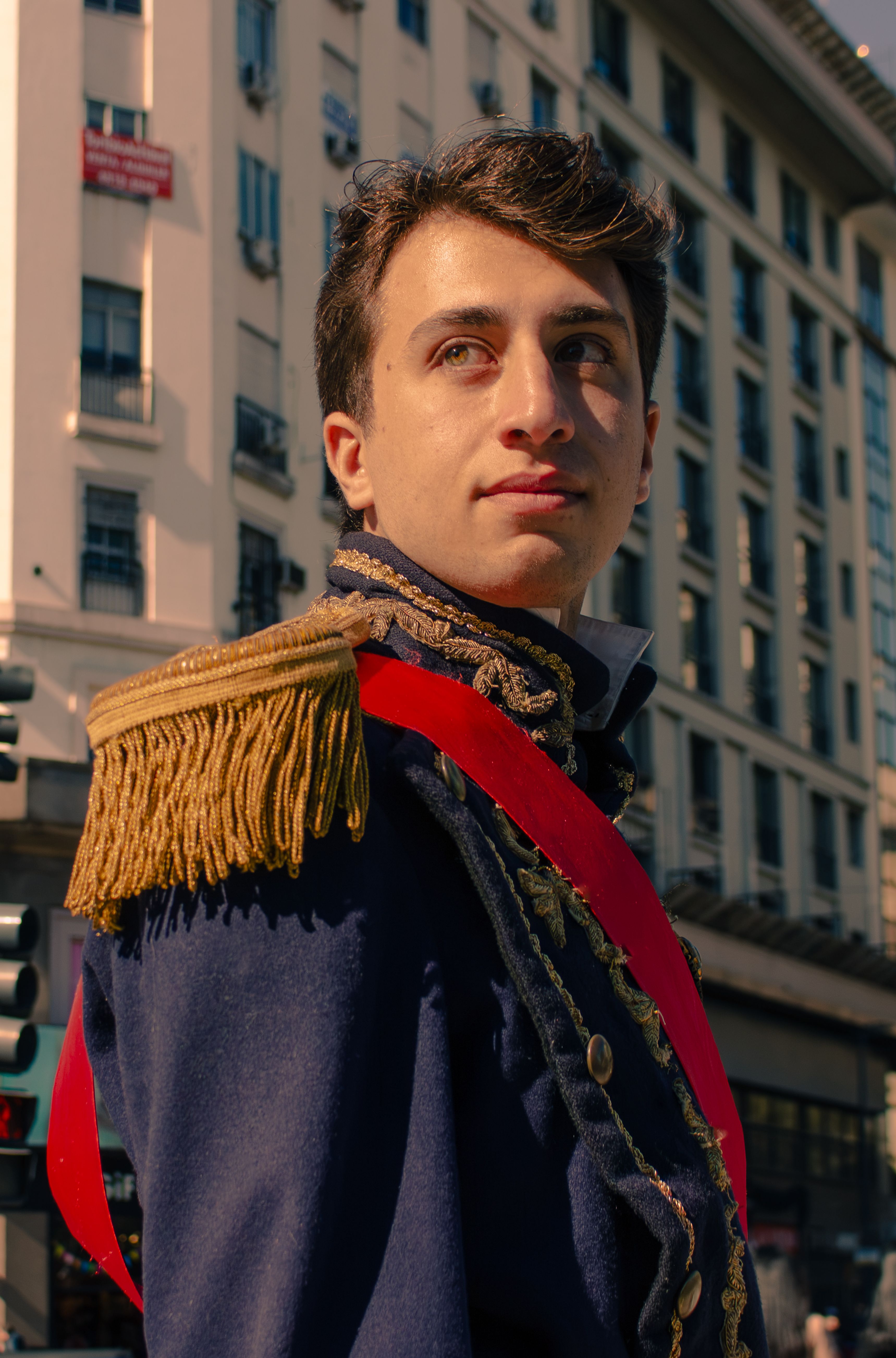 Man in a historical military uniform standing outdoors in Buenos Aires, Argentina with a classic building background.