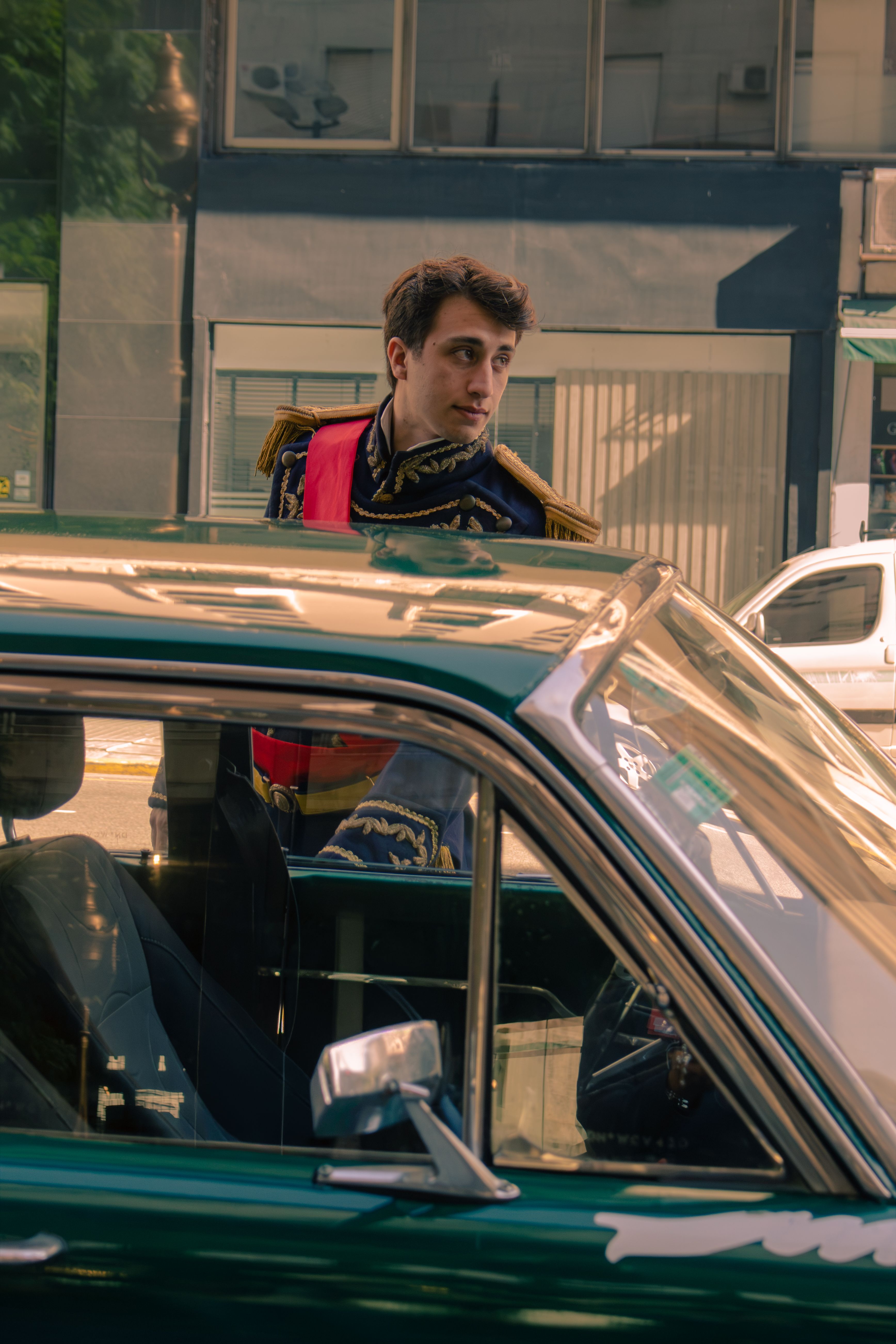 A man in a historical uniform stands beside a classic car in Buenos Aires.