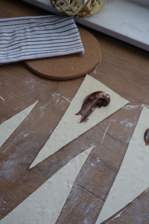 Free Raw dough triangles with chocolate spread ready for baking croissants. Stock Photo