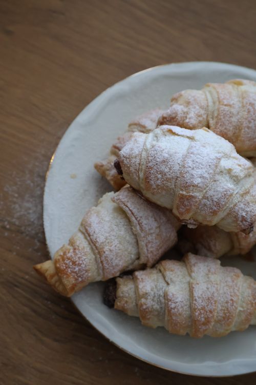 Free Plate of freshly baked croissants dusted with powdered sugar, perfect for breakfast. Stock Photo