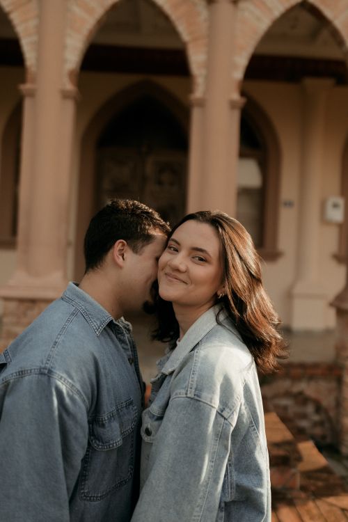 Free A happy couple in denim sharing an intimate moment in front of rustic arches. Stock Photo
