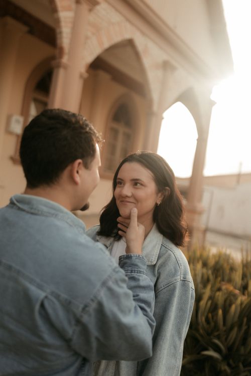 Free A young couple sharing a tender moment at sunset outside a historical building. Stock Photo