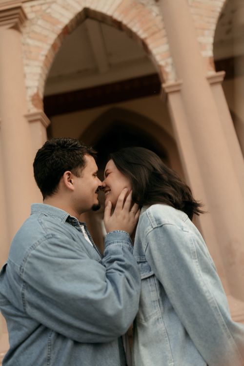 Free A couple sharing a tender moment under an ornate archway, evoking romance and architectural elegance. Stock Photo