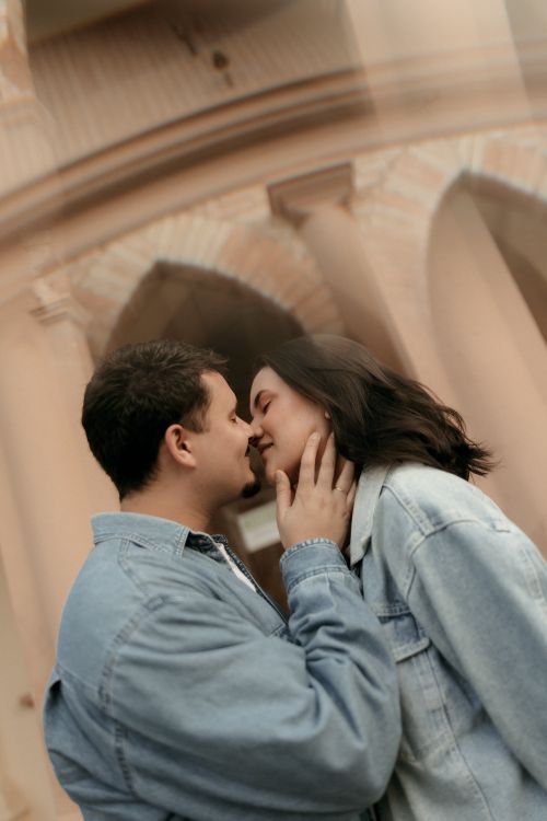 Free A couple sharing a romantic moment in front of an elegant architectural backdrop. Stock Photo