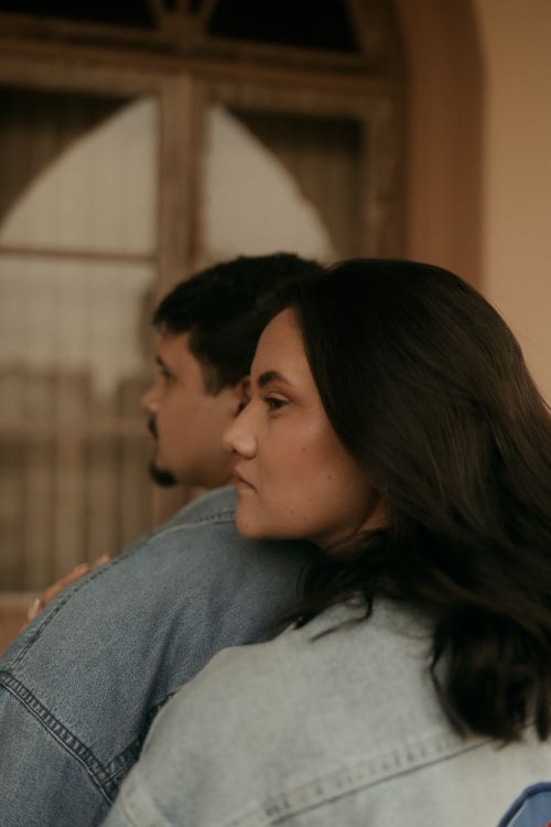Free A warm portrait of a couple embracing indoors, conveying love and intimacy in soft, muted lighting. Stock Photo