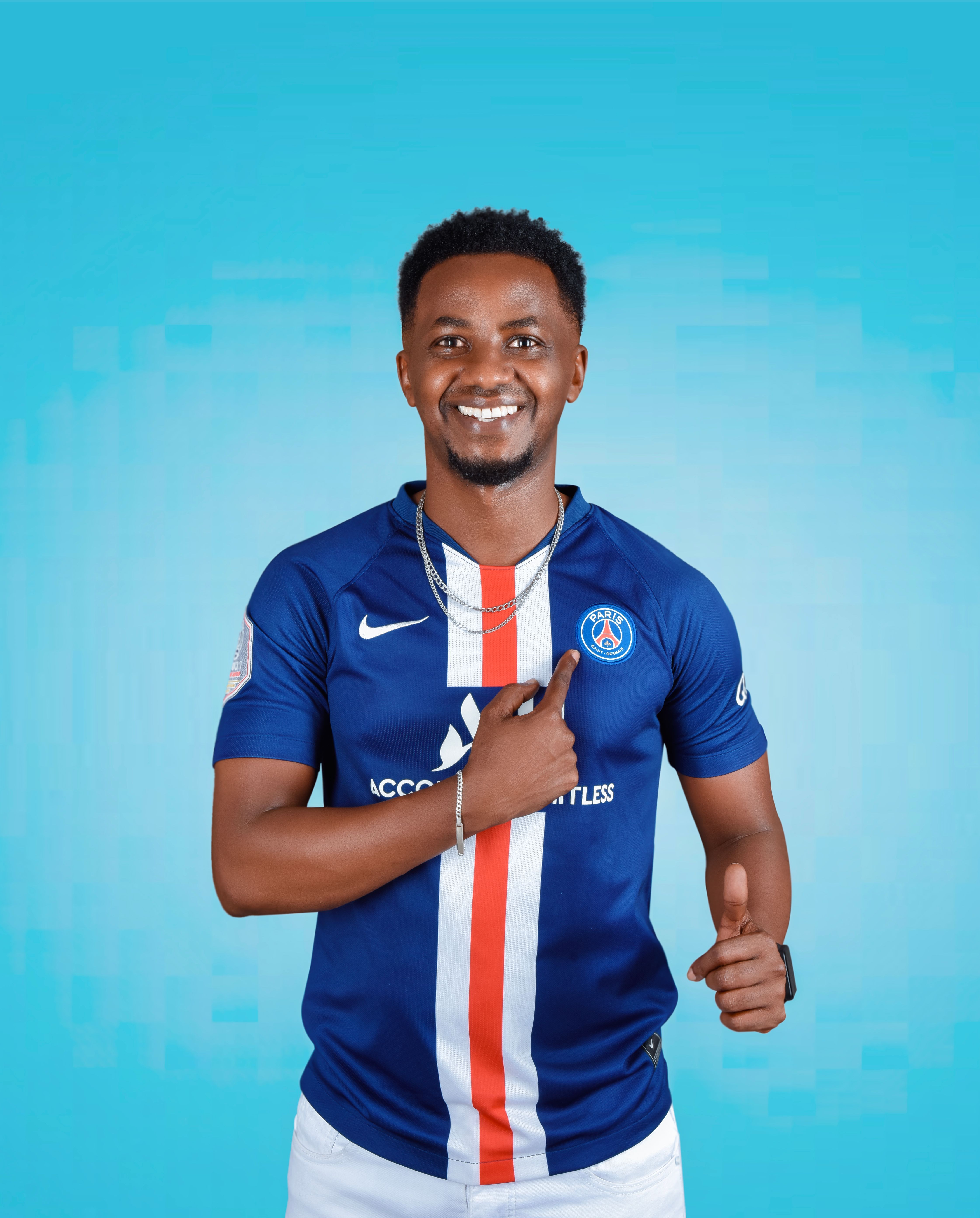 Young man wearing a blue sports jersey smiles against a vibrant blue background.