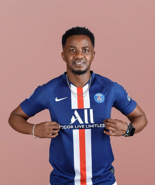 Free Smiling man showing PSG jersey against a neutral background, expressing sports enthusiasm. Stock Photo