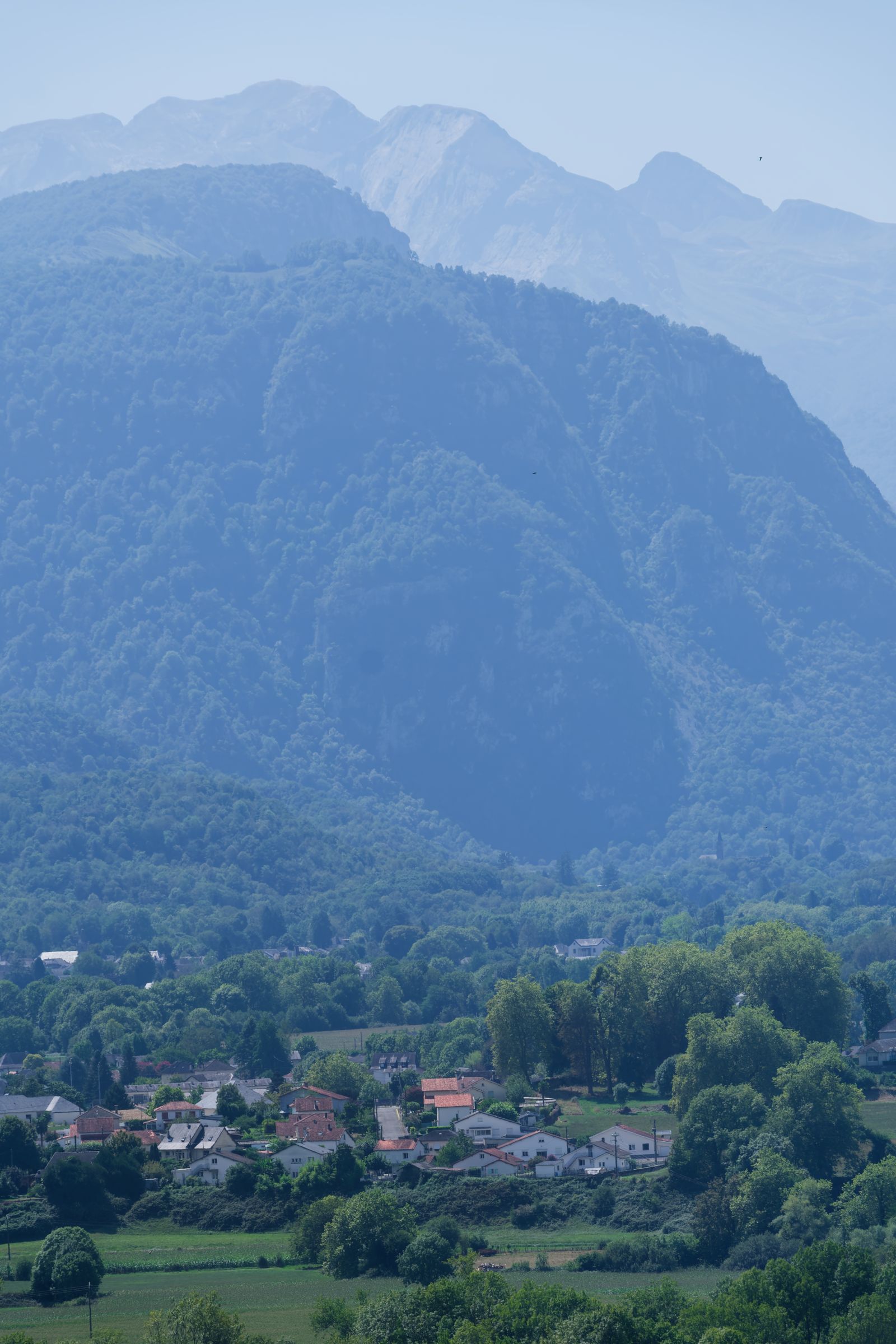 Les sommets des Pyrénées dominent un village brumeux, près de Pau