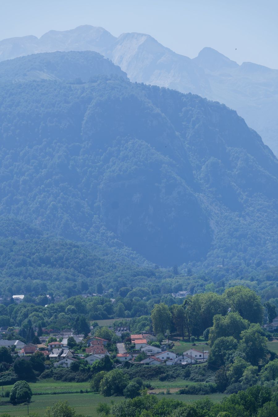 Pyrenees peaks rise above a misty valley village near Pau, France