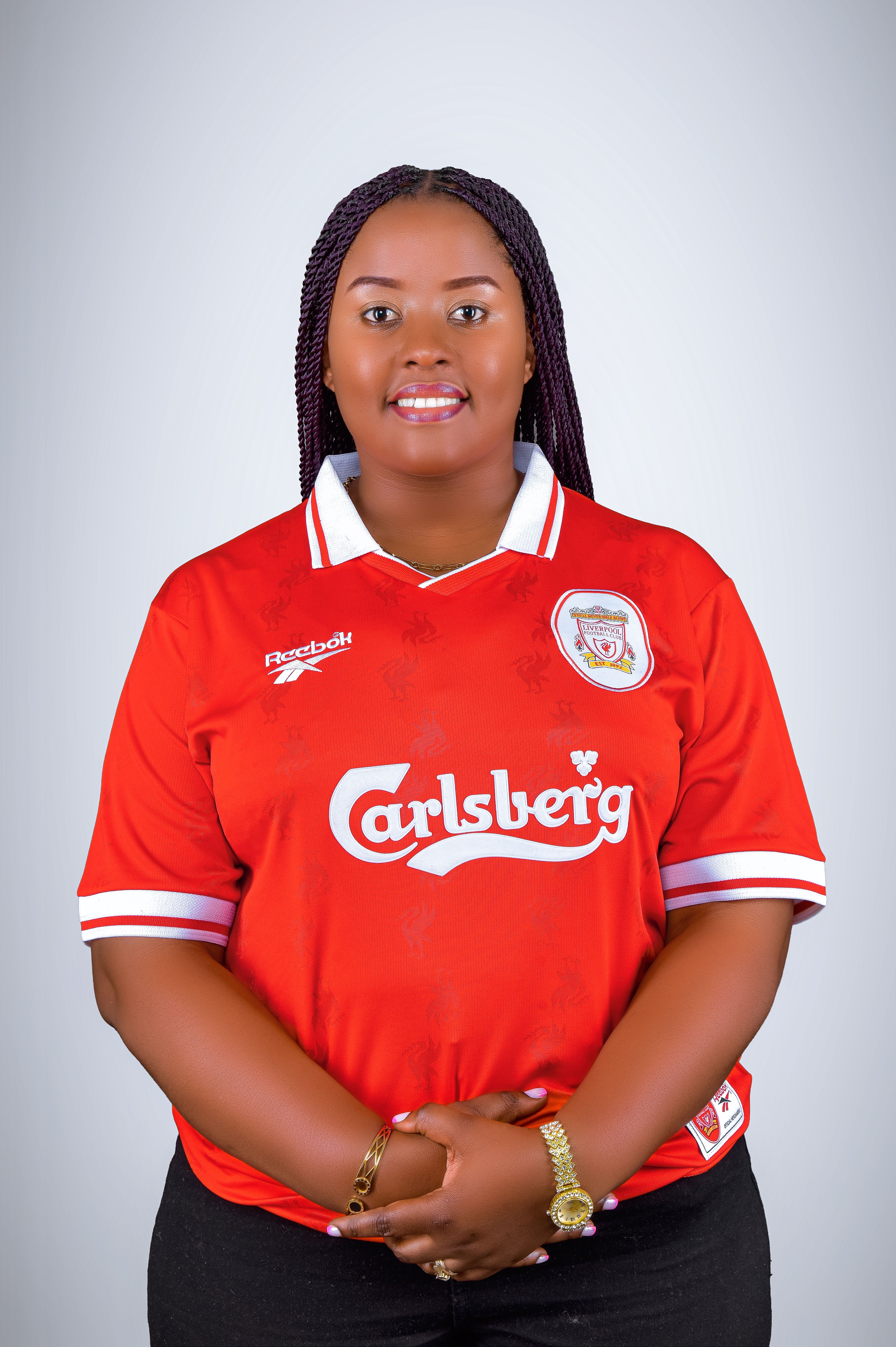 Confident woman in a red sports jersey posing with a smile against a light background.