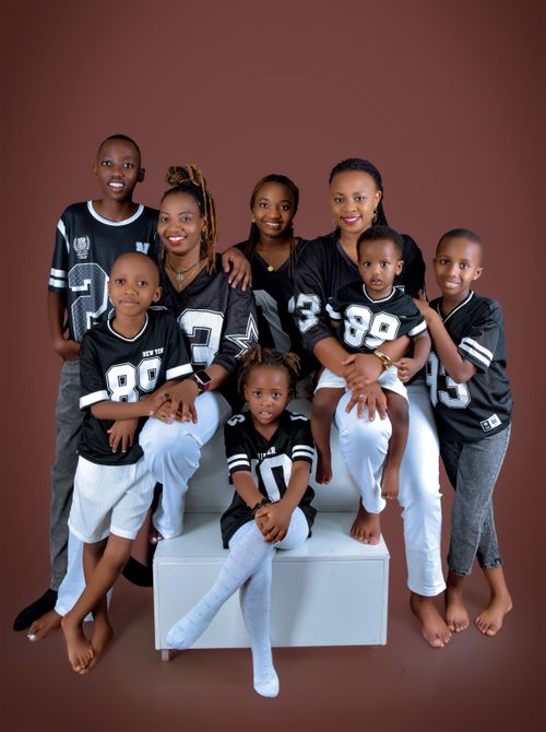 Free Smiling multigenerational African family wearing matching sports jerseys in a studio setting. Stock Photo