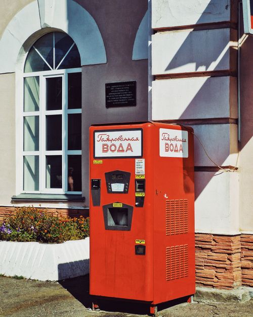 Free Retro red soda vending machine against building facade, summertime setting. Stock Photo