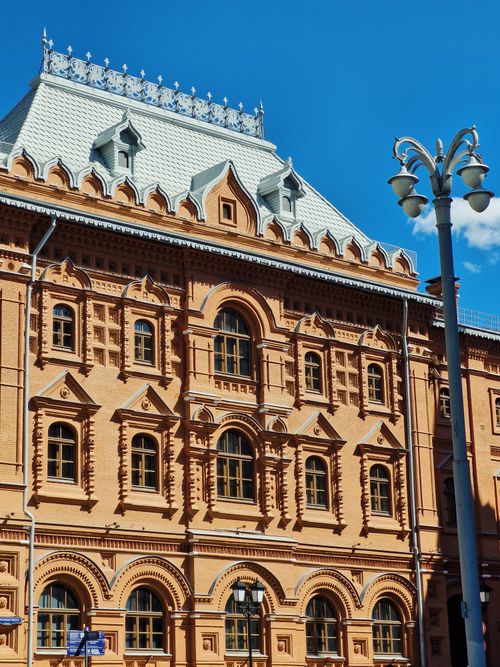 Free Elegant red brick building with detailed architectural designs under a clear blue sky. Stock Photo