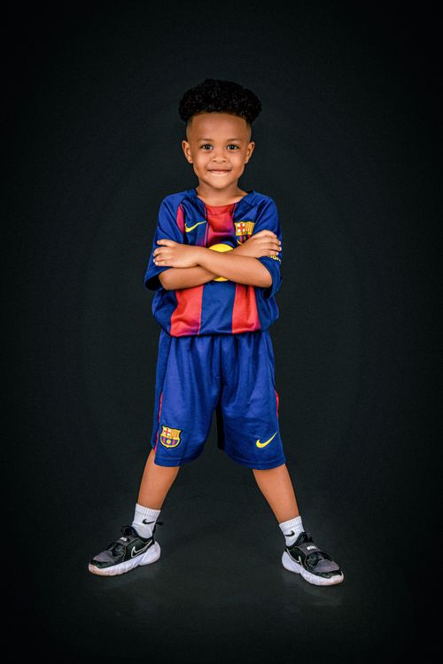Free Smiling child in soccer jersey posing confidently on a dark background. Stock Photo