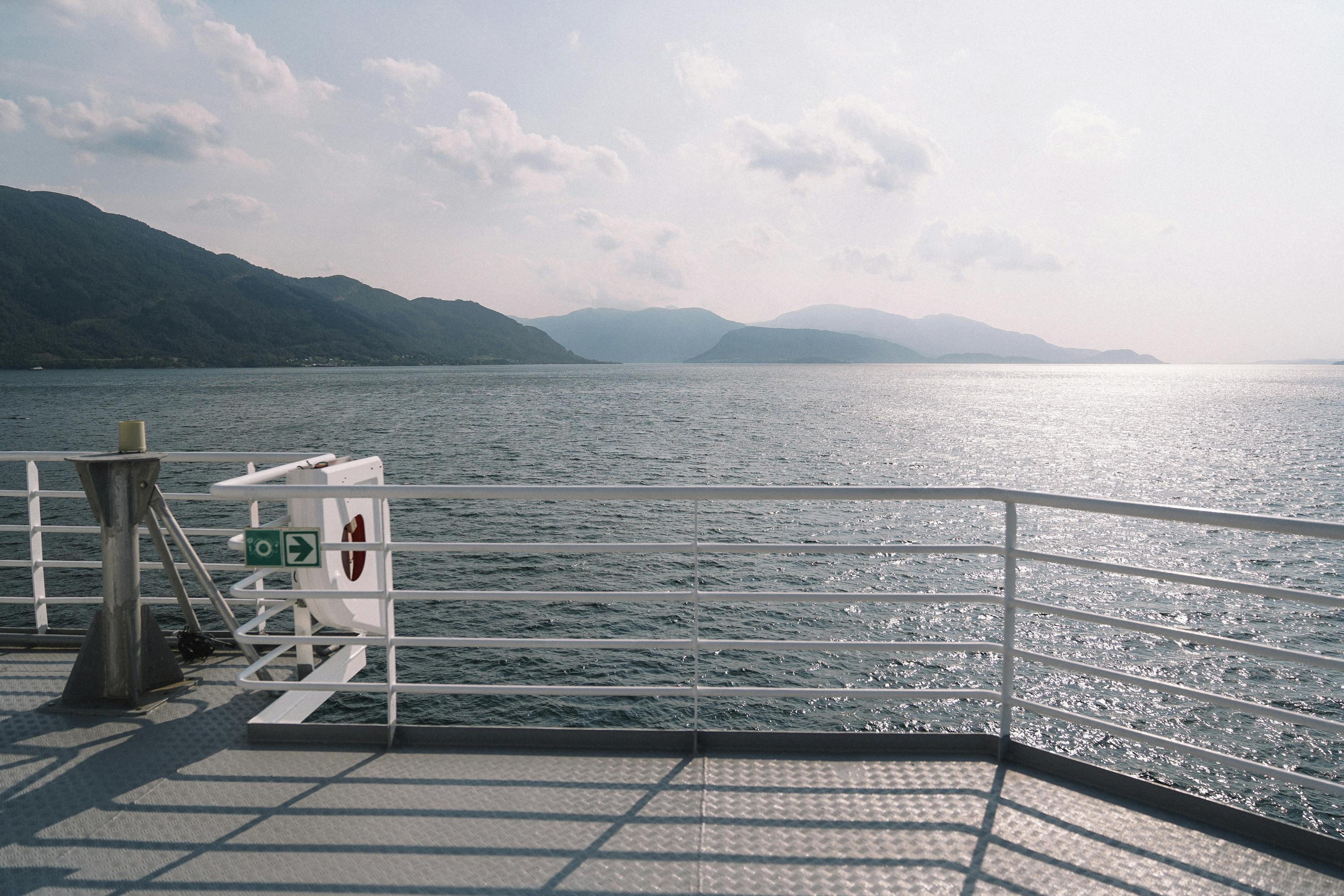 Free Scenic view of ocean and mountains from a boat deck, perfect for travel inspirations. Stock Photo