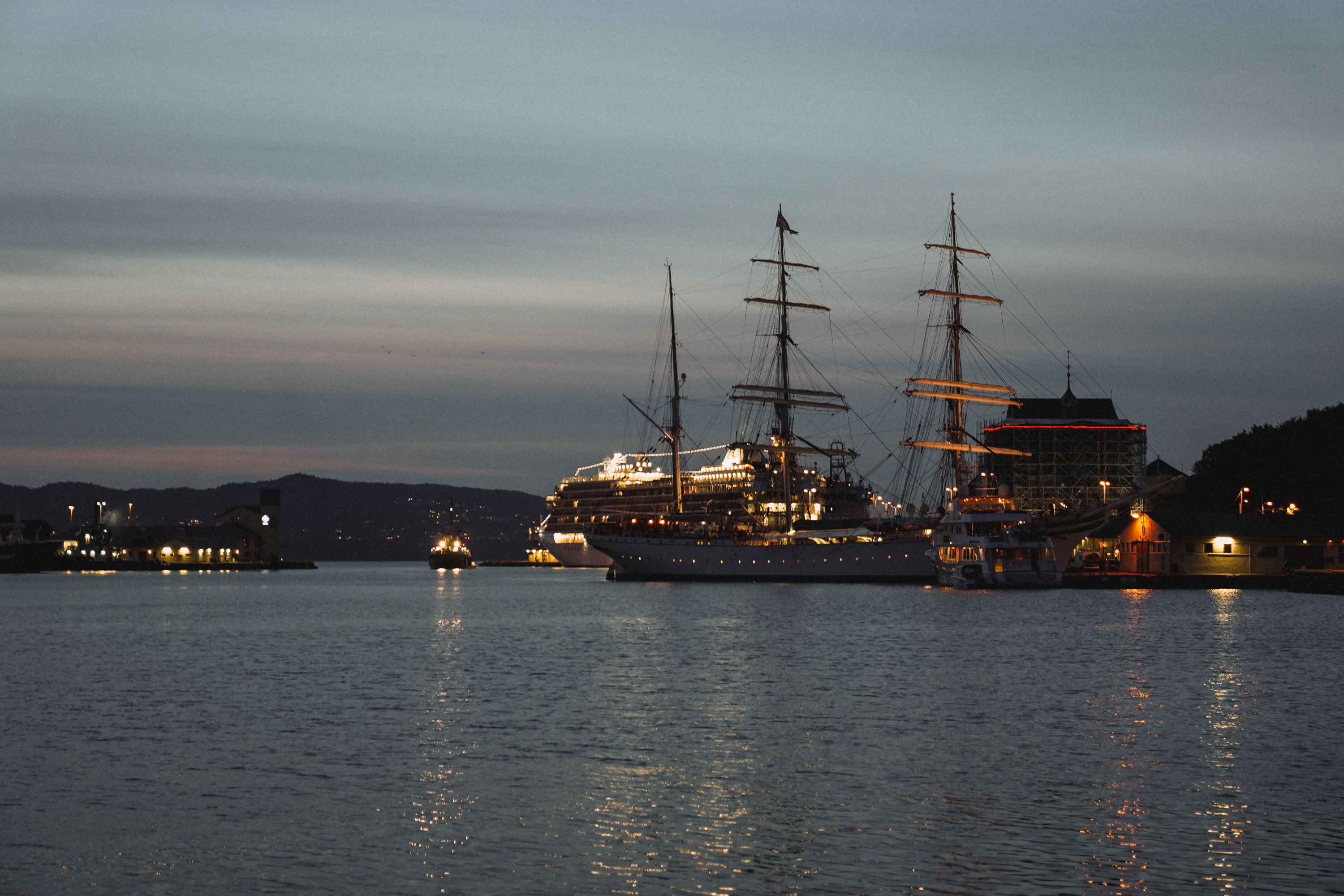 A tranquil view of ships and masts in a Norwegian harbor at twilight.