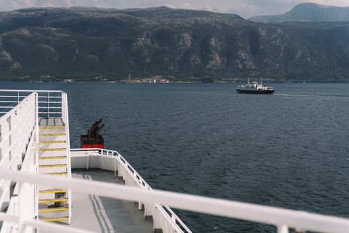 Free Ferry traversing a serene sea against a majestic mountain backdrop, capturing nautical elegance. Stock Photo