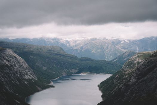 Breathtaking view of a Norwegian fjord surrounded by rugged mountains under a dramatic sky.