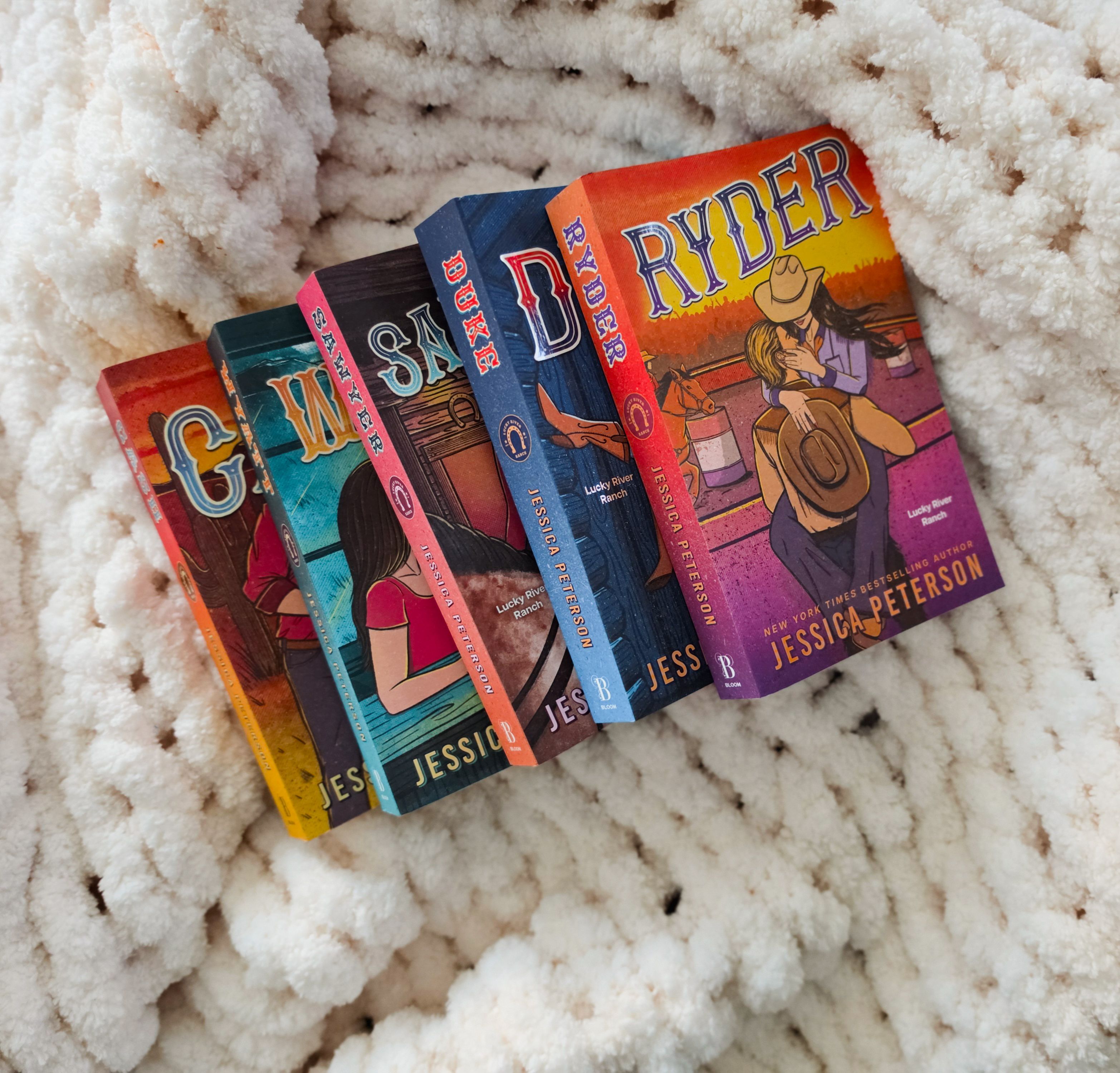 A vibrant collection of romance novels by Jessica Peterson resting on a plush white blanket, creating a cozy reading vibe.