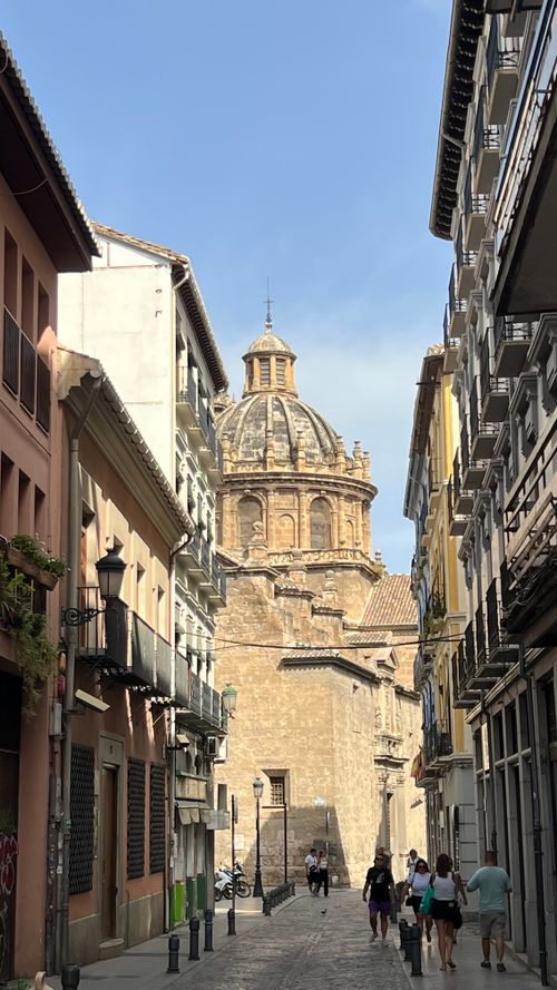 Free Charming street scene in Granada, Spain with views of the historic cathedral dome on a sunny day. Stock Photo