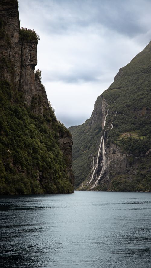 Free Dramatic cliffs and waterfall in Geirangerfjord, Norway, showcasing breathtaking natural beauty. Stock Photo