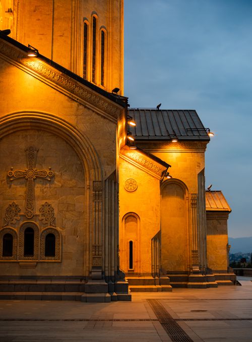 Free A beautifully lit ancient cathedral facade showcasing detailed carvings and warm lighting at dusk, enhancing its majestic architecture. Stock Photo
