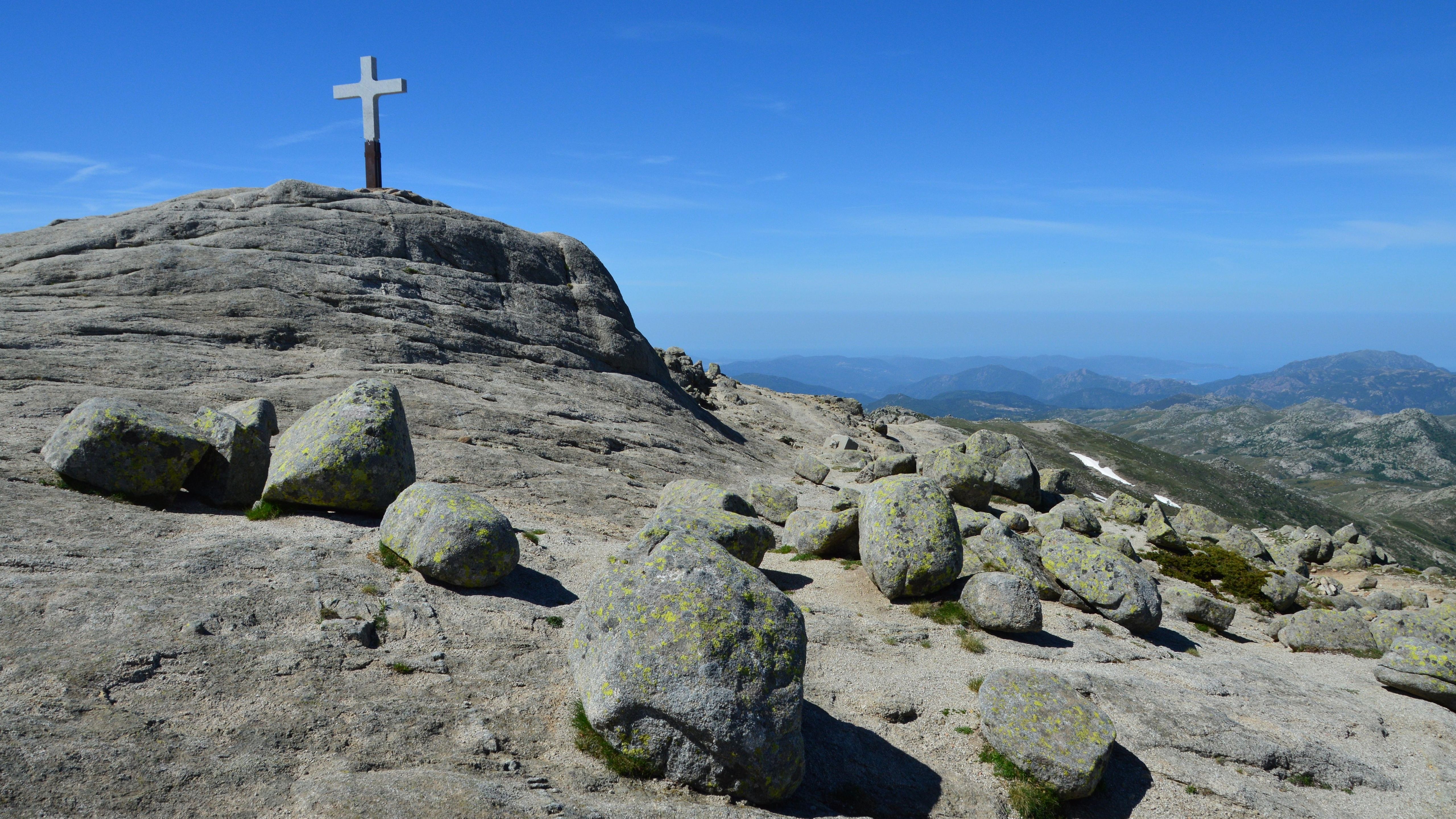 Majestic view of rocky landscape with a cross in Quenza, Corsica, under a clear blue sky.