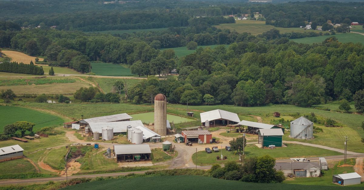 Scenic aerial view of a traditional American farm surrounded by lush greenery and fields.