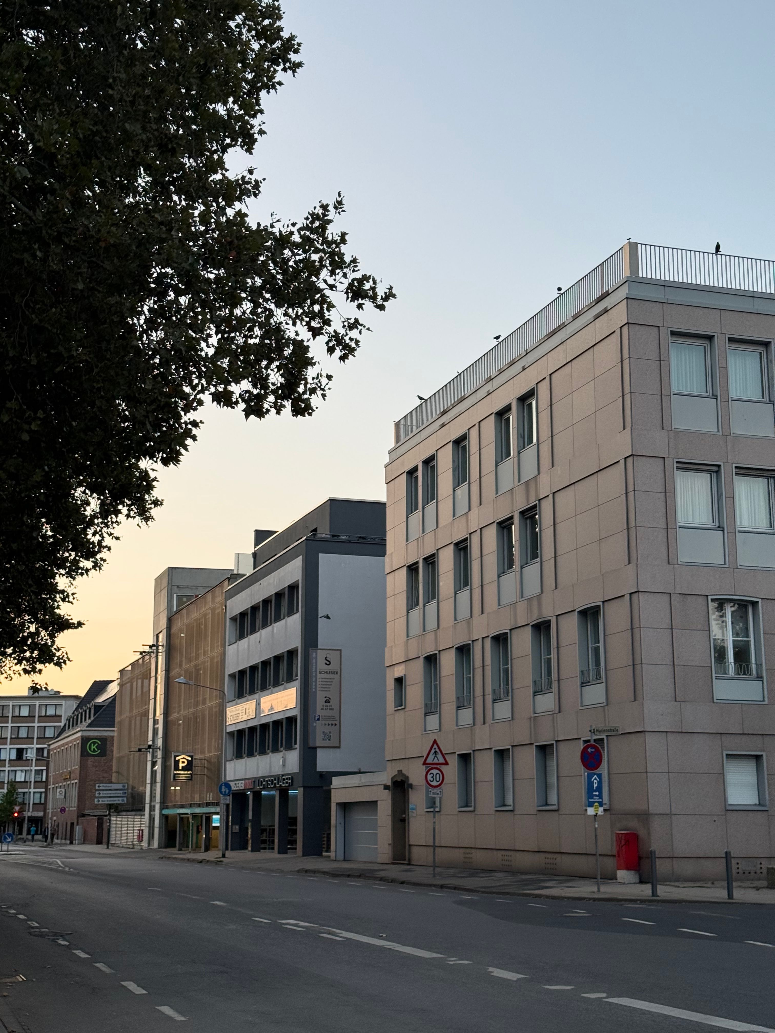 Quiet urban street scene at dusk featuring modern buildings in Düren, Germany.