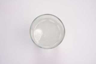 Top-down view of a tablet dissolving and fizzing in a glass of water
