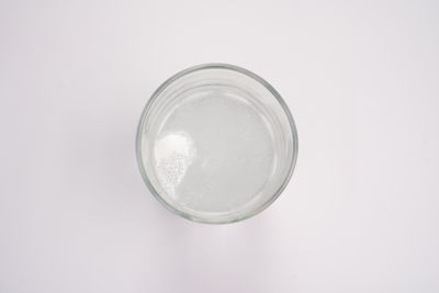 Top-down view of a tablet dissolving and fizzing in a glass of water