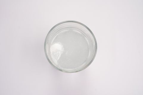 Top-down view of a tablet dissolving and fizzing in a glass of water