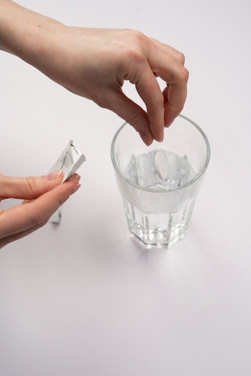 Person Putting White Tablet In Drinking Water