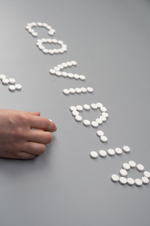 Free White pills arranged to spell 'COVID' on a gray table with a hand arranging them, symbolizing healthcare efforts. Stock Photo