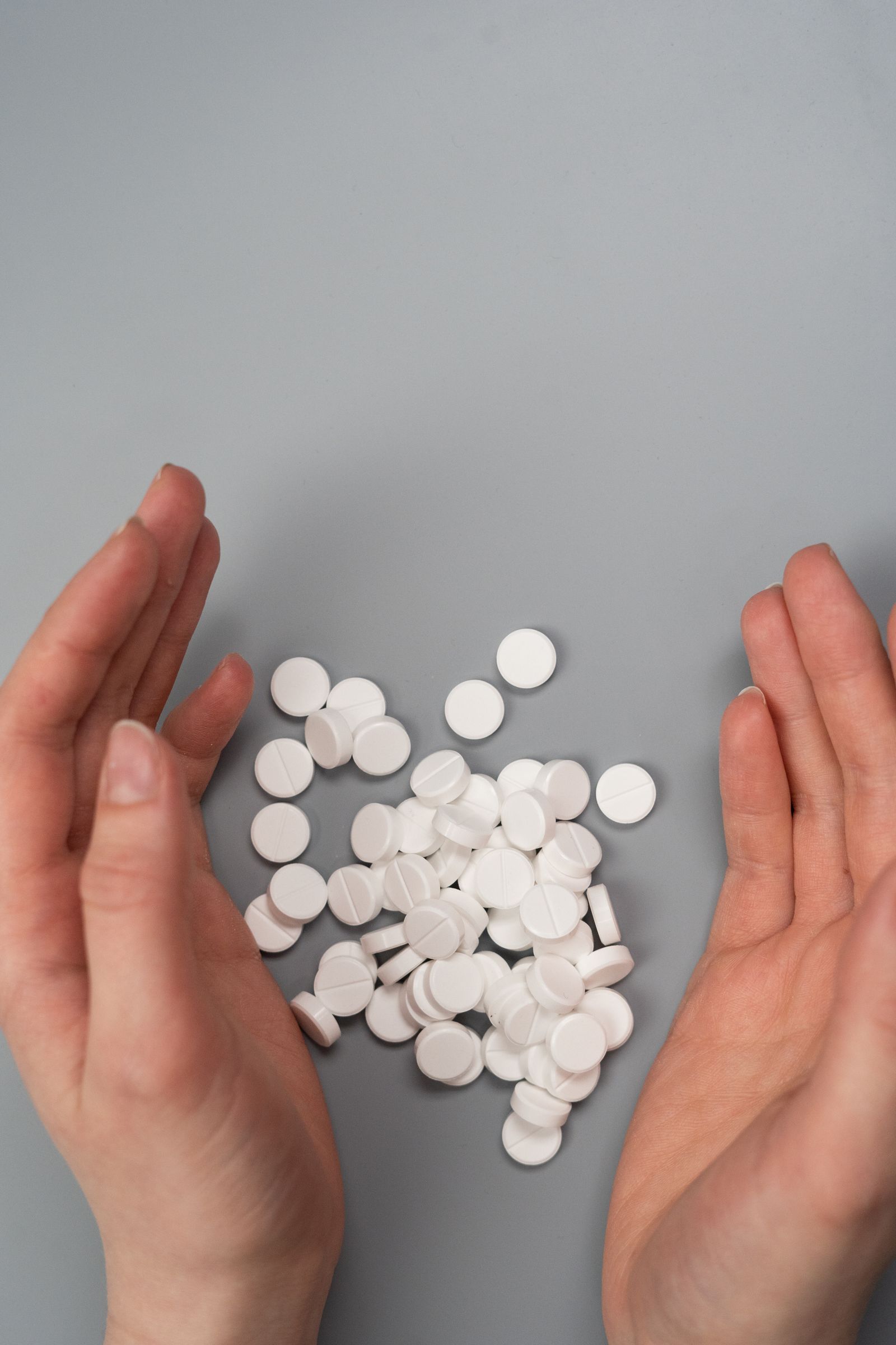 Hands surrounding medication pills representing prescription drug and opioid misuse