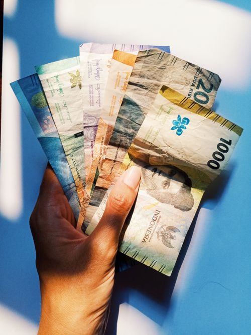 Free A hand holding various international currency notes, highlighted in natural light. Stock Photo