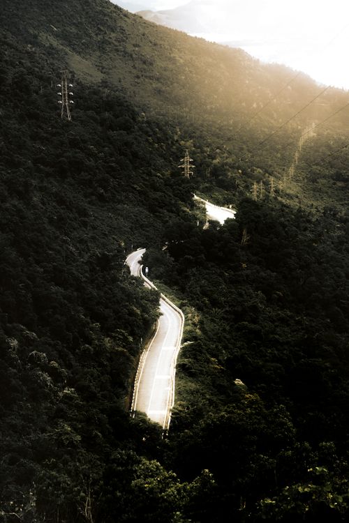 Free Aerial view of a scenic winding road through lush green mountains in Da Nang, Vietnam. Stock Photo