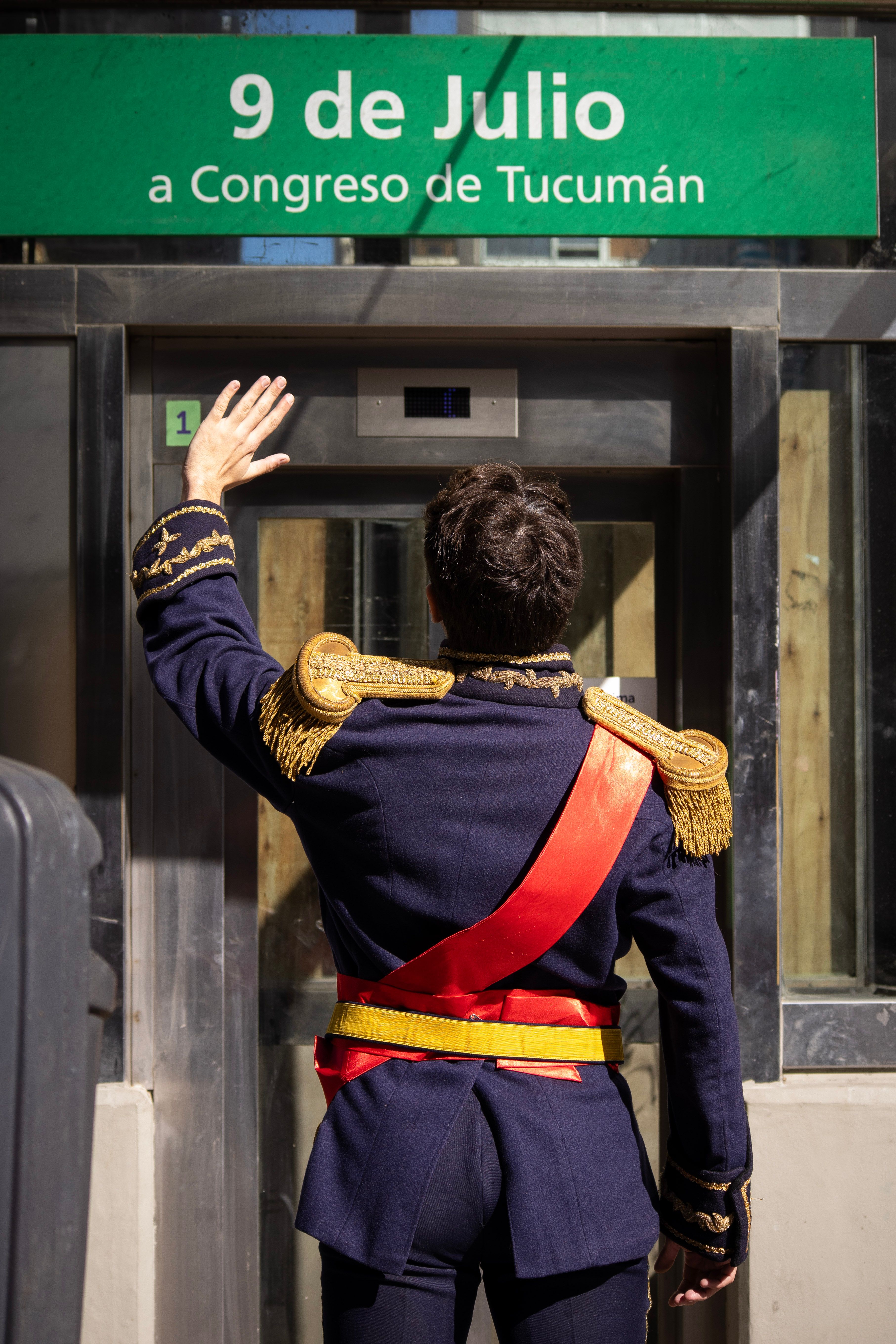 Person in military uniform saluting subway entrance with '9 de Julio' sign in Buenos Aires.