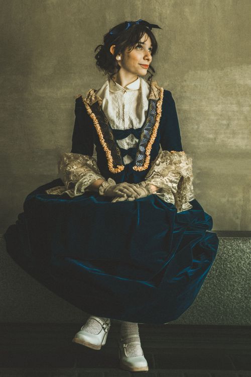 Free A woman in Victorian-style attire posing indoors with a warm, classic mood. Stock Photo