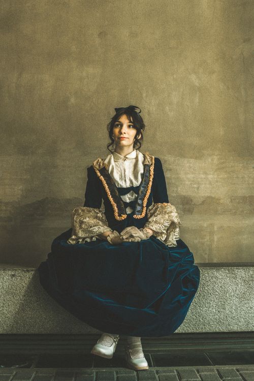 Free A woman in Victorian attire sits indoors, evoking a vintage vibe. Stock Photo