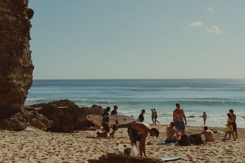 Free A vibrant beach scene in Bali, with surfers and sunbathers enjoying the sunny day by the ocean. Stock Photo
