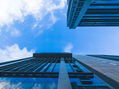 Dynamic upward view of modern skyscrapers against a blue sky in Bengaluru, India.