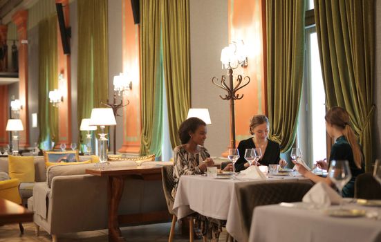 Three friends enjoying a sophisticated meal in a stylish restaurant setting with vintage decor.