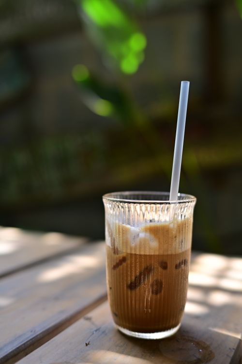 Free Close-up of a glass of iced coffee with cream, served outdoors in natural light. Stock Photo