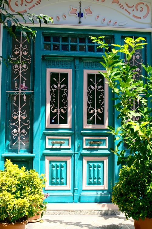 Free Charming turquoise wooden door with intricate ironwork, framed by lush plants. Stock Photo
