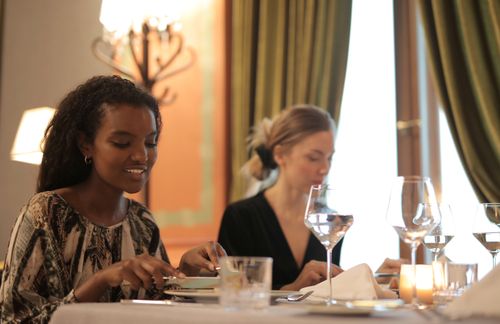Free Two women enjoying a refined dining experience in a stylish restaurant setting. Stock Photo