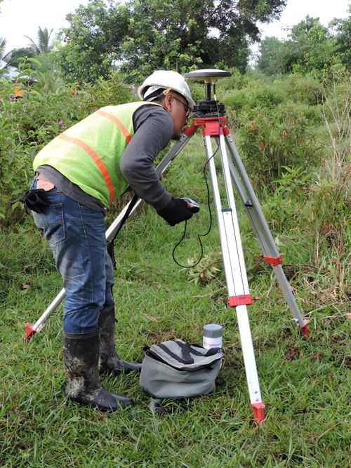Free A surveyor using equipment in lush Indonesian terrain, wearing safety gear. Stock Photo