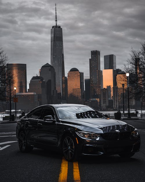 Free Black Sedan On The Road Near City Buildings Stock Photo