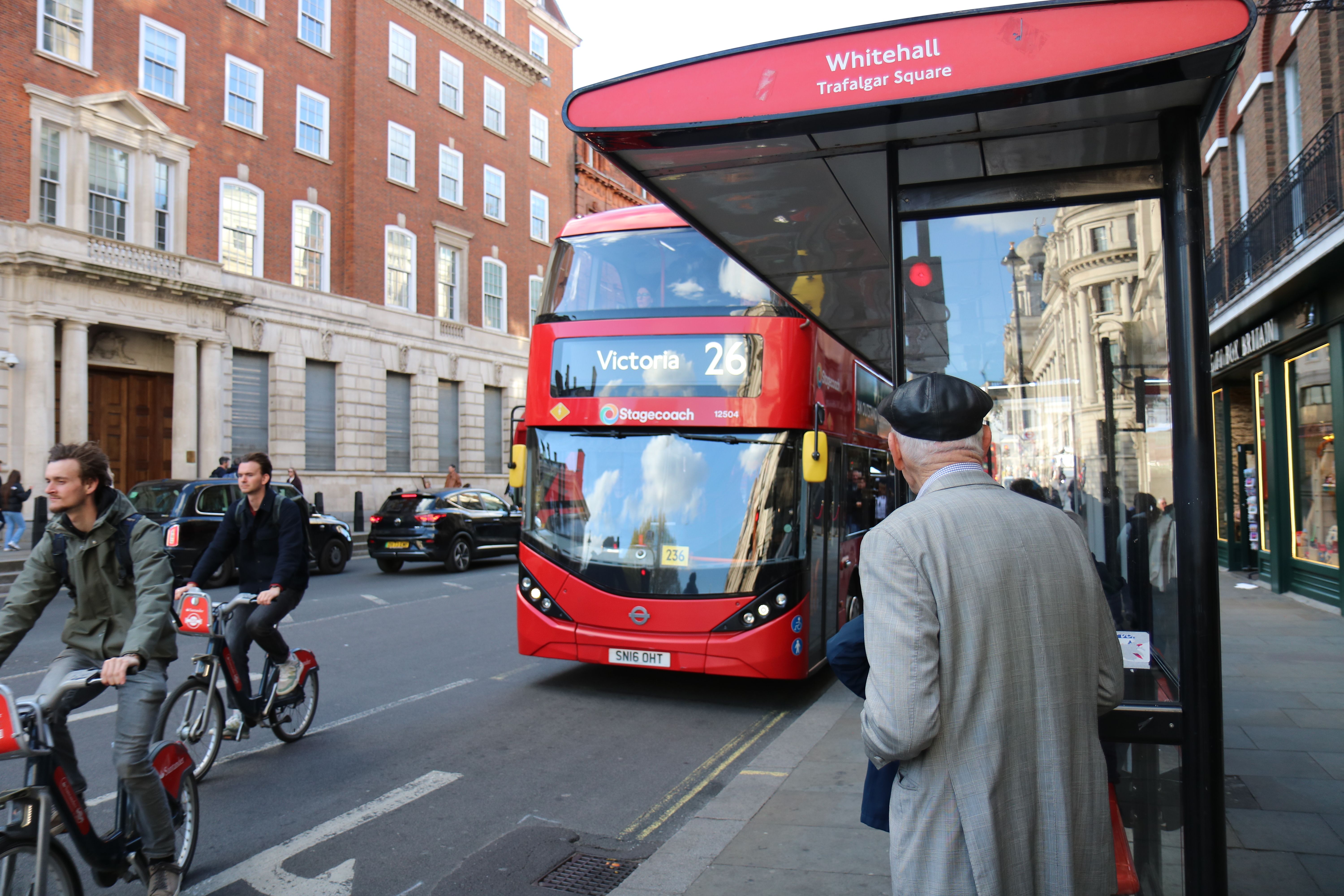 A classic red double-decker bus at a London bus stop near Whitehall and Trafalgar Square.