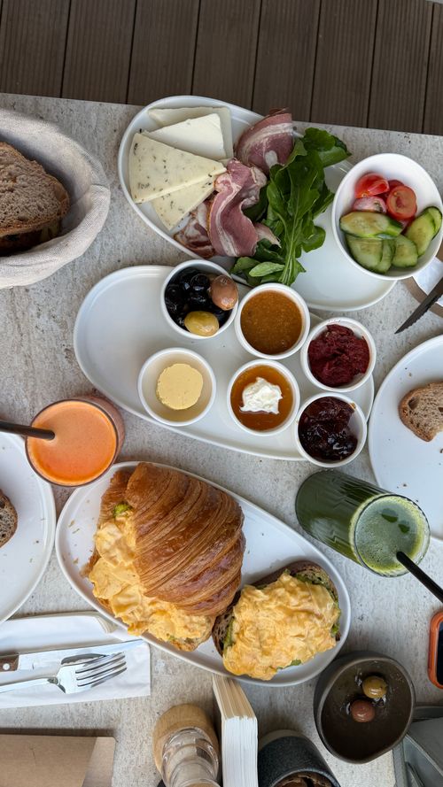 Free A vibrant Turkish breakfast featuring fresh vegetables, cured meats, cheese, spreads, and a croissant on a laid table. Stock Photo